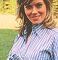 Wendy Richard kneeling on grass, wearing a blue and white striped shirt